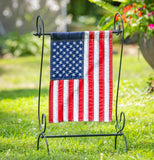 American flag on a decorative stand in a garden setting