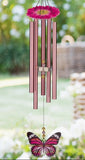 Pink wind chime with butterfly design in a garden setting