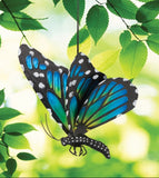 Decorative butterfly with blue and green wings hanging among green leaves.