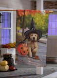 Decorative Halloween banner with a dog wearing a witch hat and holding a broomstick in front of pumpkins on a porch.