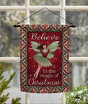 Decorative Christmas flag with fairy design and text 'Believe in the magic of Christmas' hanging in front of a window.