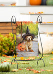 Decorative stand with a photo of a dog in a witch hat surrounded by pumpkins and autumn leaves.