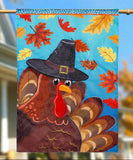 Decorative flag with a turkey wearing a pilgrim hat on a blue background with autumn leaves.