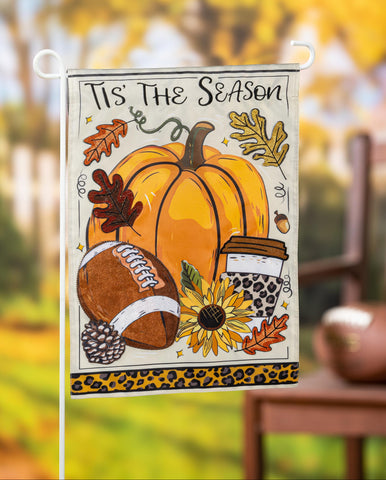 Decorative garden flag with autumn elements and 'Tis the Season text, displayed outdoors.
