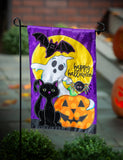 Halloween-themed garden flag with a ghost, black cat, and pumpkin in front of pumpkins.