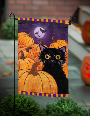 Halloween-themed garden flag with a black cat and pumpkins, placed outdoors.