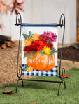 Decorative garden flag with pumpkins and flowers on a stand outdoors.
