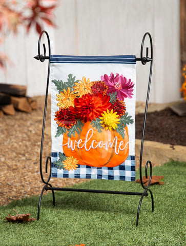 Decorative garden flag with pumpkins and flowers on a stand outdoors.