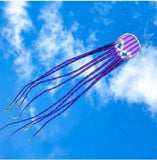 Purple jellyfish kite against a blue sky with white clouds