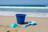 Blue sand bucket, shovel, and turtle toy with a blue mesh bag on a white background.
