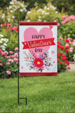 Valentine's Day decorative flag with pink heart and floral design on a house exterior.