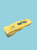 Yellow butter container with 'Butter' branding on a concrete surface
