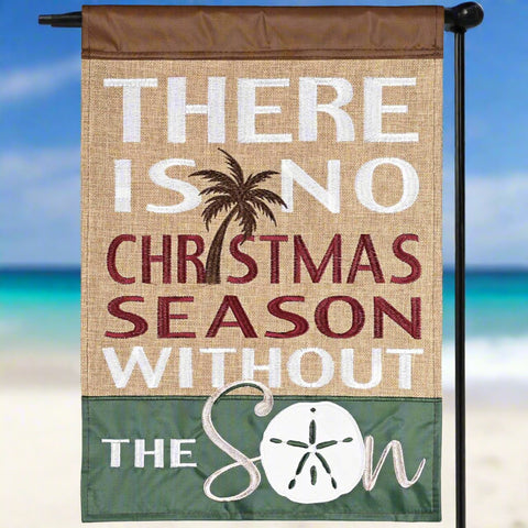 Decorative flag with Christmas message and beach elements against a blurred beach background
