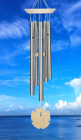 Wind chime hanging against a blue sky with clouds and ocean view