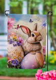 Decorative garden flag with a bunny and Easter eggs on a blurred outdoor background