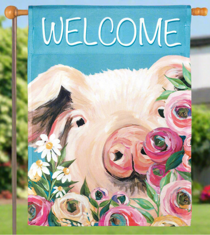 Decorative flag with a pig's face surrounded by flowers and the word 'WELCOME' on a blue background.